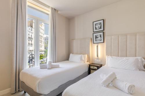 two beds in a hotel room with a window at Valencia Apartamentos Goya in Valencia