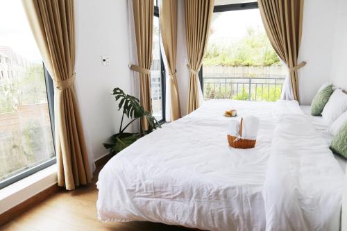 a bedroom with a white bed with a window at Enjoy Villa Da Lat in Khu Chi Lăng