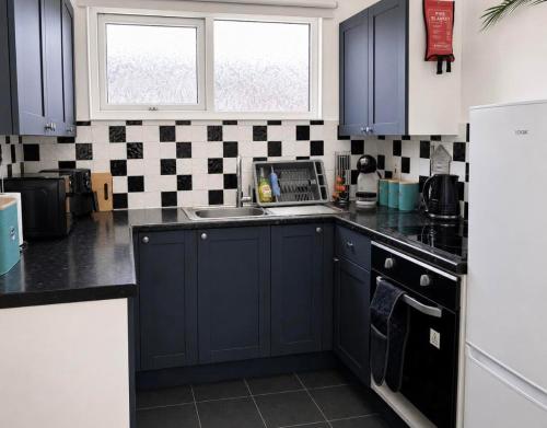 a kitchen with blue cabinets and a sink at Seashells - Chalet 25 in Greatstone