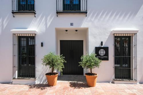 a white building with two potted plants in front of a door at Hotel Estepona Patio in Estepona