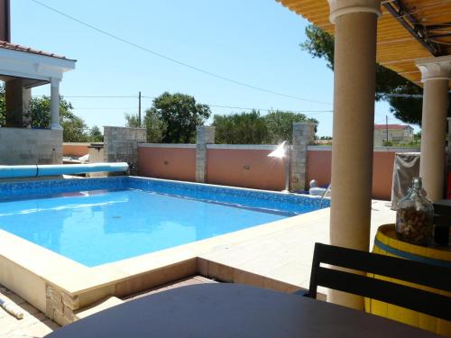 a swimming pool in a patio with a table and a chair at Apartment Valerija in Privlaka