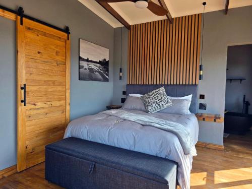 a bedroom with a large bed and a wooden door at Renosterveld Eco Pods in Swellendam
