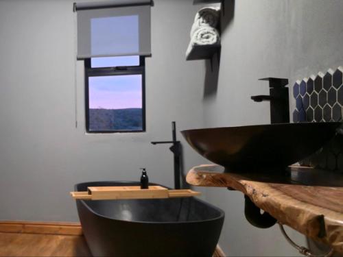 a bathroom with a black sink and a wooden counter at Renosterveld Eco Pods in Swellendam