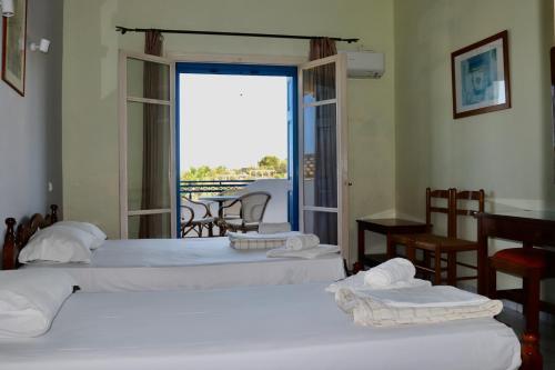 two beds in a room with a view of a balcony at Orama Hotel in Sígrion