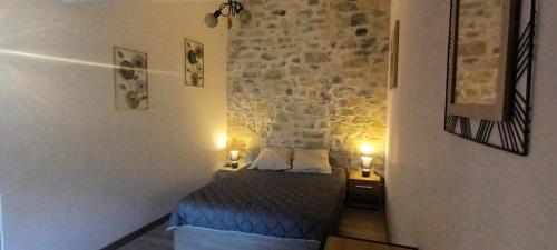 a bedroom with a bed and a stone wall at Gîte Le Citronnier - Piscine partagée in Lagorce