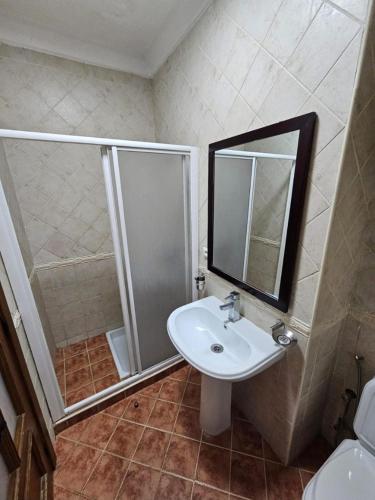 a bathroom with a sink and a shower with a mirror at Jawhara smir 2ET vue piscine in M'diq