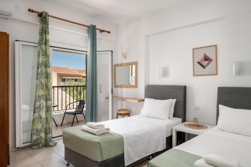a bedroom with two beds and a balcony at Dora Pool Studios by Konnect,150m from the Beach in Agios Georgios