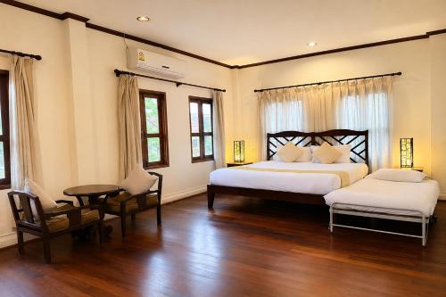 a bedroom with two beds and a table and chairs at Luang Prabang Legend Hotel in Luang Prabang