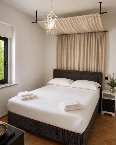 a bedroom with a large white bed with a chandelier at Domo s'Altura in Porto Rotondo