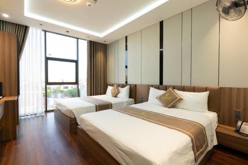two beds in a hotel room with windows at Viet Phuong Center Hotel in Ninh Binh