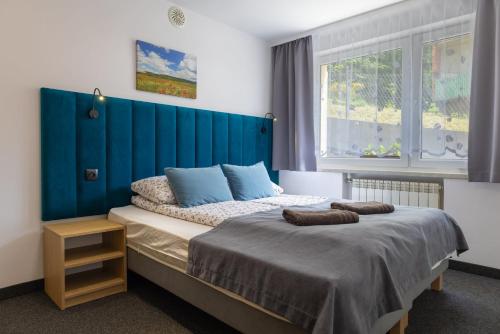 a bedroom with a bed with a blue headboard at Willa Mak in Krynica Zdrój