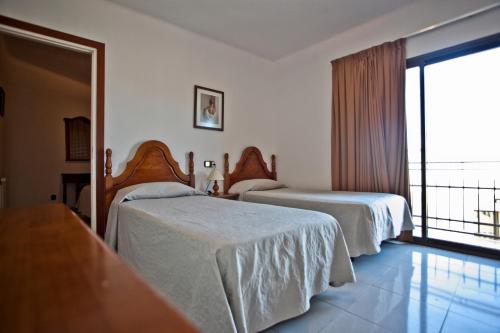 a hotel room with two beds and a balcony at Hotel Beri - Can Llançà in Llança