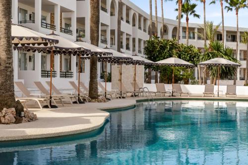 a hotel swimming pool with chairs and umbrellas at Wyndham Mallorca Portocolom Resort in Portocolom
