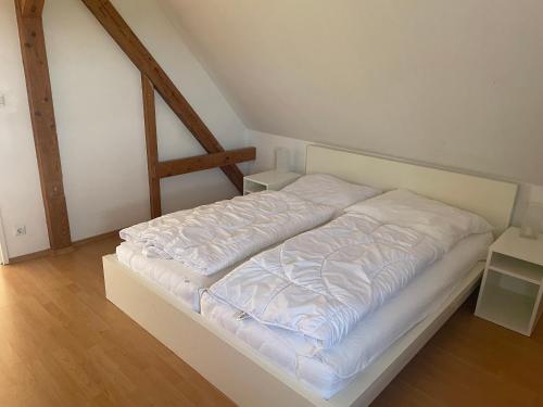 a white bed in a room with wooden floors at Haus Mediterran in Kamień Pomorski