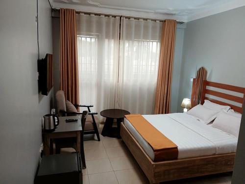 a bedroom with a bed and a table and a desk at Spark Africa Hotel in Jinja