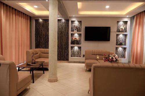 a waiting room with couches and a flat screen tv at Spark Africa Hotel in Jinja