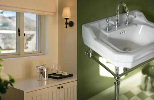 a bathroom with a white sink and a window at Maison Cabrière Boutique Hotel in Franschhoek