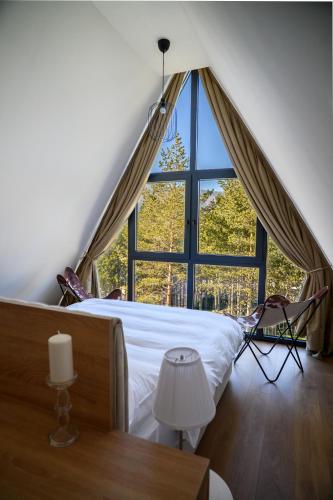 a bedroom with a bed and a large window at Woodlander Mountain House Blidinje in Blidinje