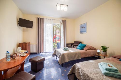 a hotel room with two beds and a table at Las i Morze - Dźwirzyno in Dźwirzyno