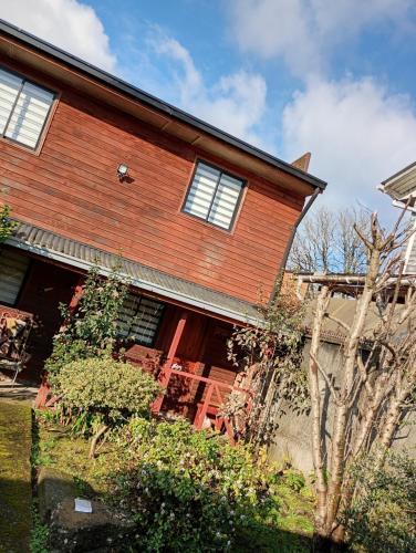 a wooden house with a tree in front of it at Hostal y Cabañas Guaje in Valdivia