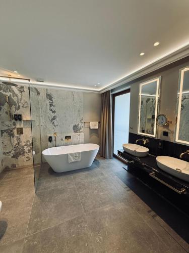 ein großes Badezimmer mit zwei Waschbecken und einer Badewanne in der Unterkunft Hotel Arkas in Proskau