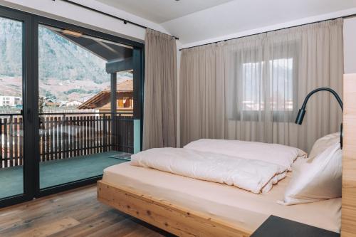 a bedroom with a bed and a large window at Malojerhof in Lana