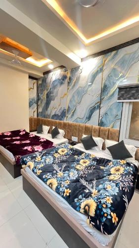 a bedroom with two beds and a painting on the wall at Hotel Kaka Inn in Ajmer