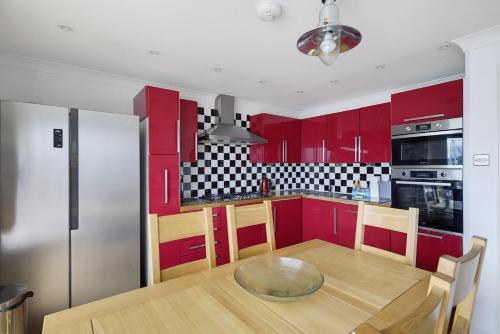 a kitchen with red cabinets and a wooden table at Marina View in Plymouth