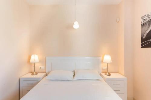 a bedroom with a white bed and two lamps at Apartamento EntreOlas in El Verger