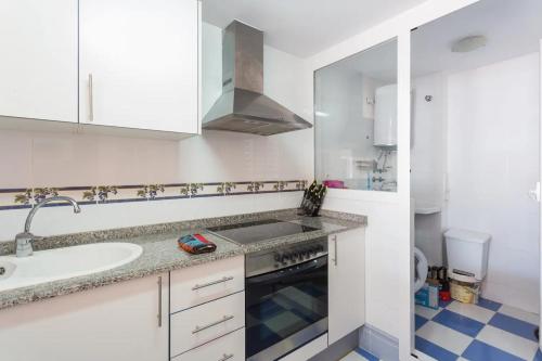 a white kitchen with a sink and a stove at Apartamento EntreOlas in El Verger
