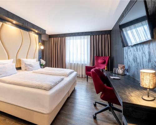a hotel room with a bed and a desk at PLAZA INN Bruchsal in Bruchsal