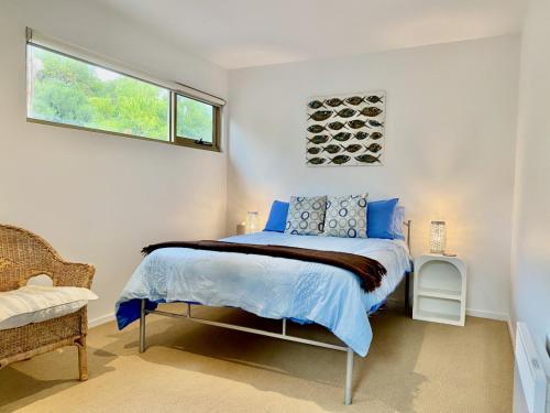 a bedroom with a bed with blue sheets and a window at Waterfront Primrose Retreat in Primrose Sands