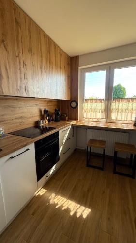 a kitchen with white cabinets and a wooden floor at Otuleni Kaszubami in Kiełpino
