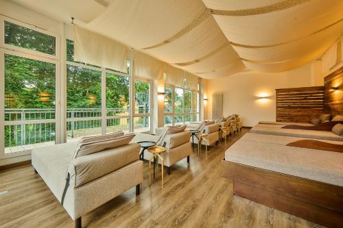 a bedroom with two beds and chairs and windows at Vitalhotel Bad Birnbach in Bad Birnbach