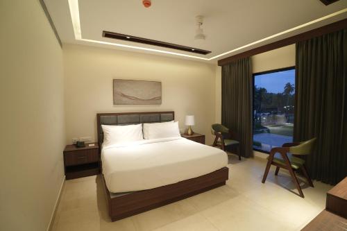 a bedroom with a bed and a large window at Mihas Hotels and Resorts in Malappuram