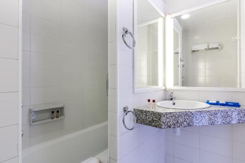 Baño blanco con lavabo y espejo en Gran Sol Hotel en San Pol de Mar