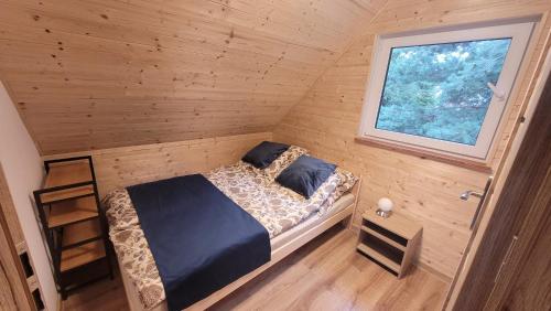 a bed in a wooden room with a window at Niebo do wynajęcia in Kłodzko