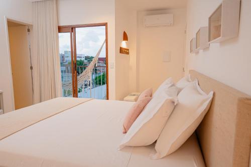 a bedroom with a large white bed with a window at Casa Aia - Hospedagem de Charme na Atalaia in Aracaju
