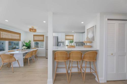 a kitchen and dining room with white cabinets and stools at Mermaid Lane #1 in Brighton Beach