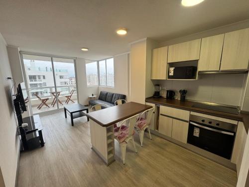 a kitchen and living room with a table and a couch at Moderno departamento cercano a playa in La Serena
