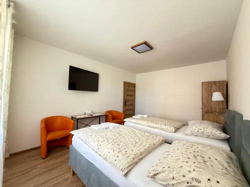 a bedroom with two beds and a tv on the wall at Apartmánový byt Flower in Kadaň