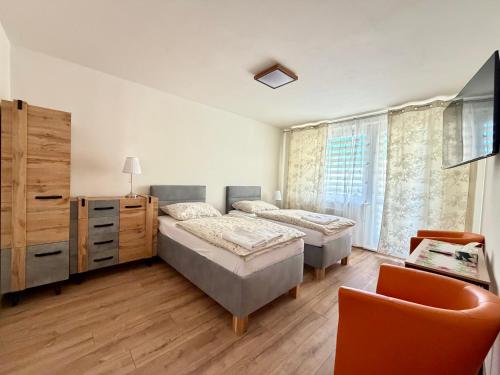 a bedroom with two beds and a chair at Apartmánový byt Flower in Kadaň