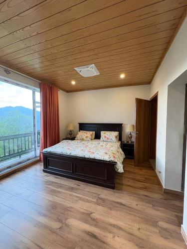 a bedroom with a bed and a large window at The Elysian Villa in Bhurban