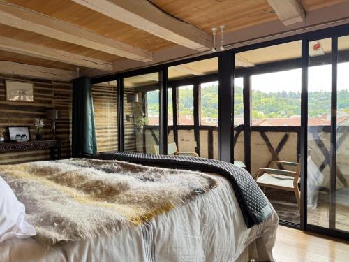 a bedroom with a bed and large glass windows at Le Soleilho in Figeac