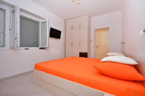 uma cama laranja num quarto branco com uma janela em Apartman Suzana em Omiš