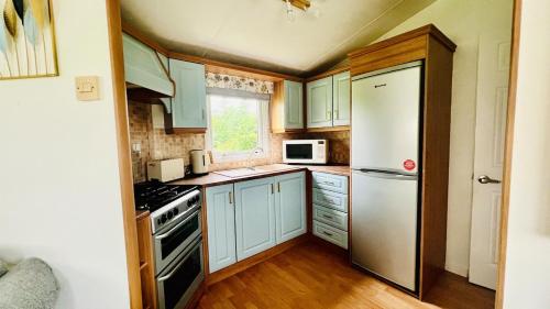 a kitchen with blue cabinets and a white refrigerator at The Hidden Meadow in Ballybofey