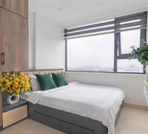 a bedroom with a bed with green pillows and a window at Ina apartment - Nera garden Hue in Hue