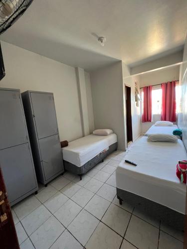 a room with two beds in it with red curtains at BG Hospedagens in Paracatu