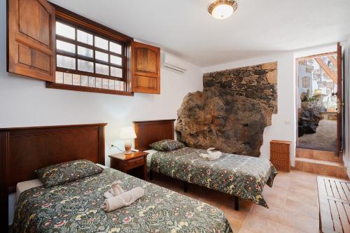 a bedroom with two beds and a rock wall at Casa Rural El Traspatio in Granadilla de Abona