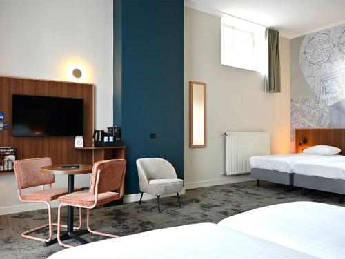 a hotel room with a bed and a table and chairs at Fletcher Hotel Paleis Stadhouderlijk Hof in Leeuwarden